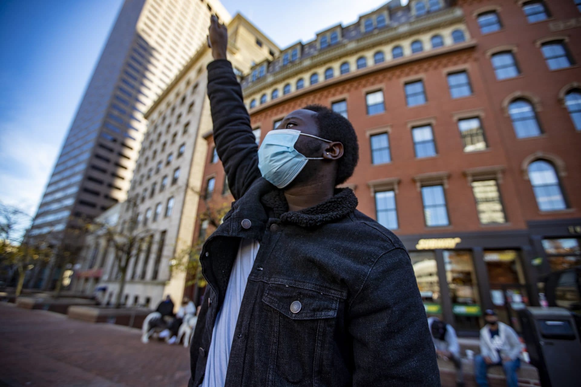 Ashawn Dabney-Small, the first 18-year-old to run for the Boston City Council, raises his fist as Monica Cannon-Grant speaks during the What this Win Means for Black Lives rally at City Hall Plaza. (Jesse Costa/WBUR)