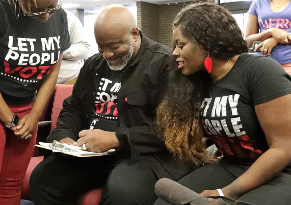 Desmond Meade (left), president of the Florida Rights Restoration Coalition, fills out a voter registration form as his wife Sheena Meade looks on at the Supervisor of Elections office in Orlando, Florida. (John Raoux, File/AP)