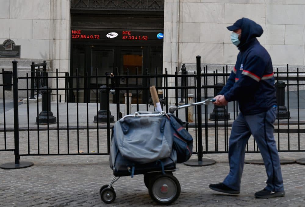A USPS mail carrier walks past the New York Stock Exchange (NYSE) at Wall Street on Nov. 16, 2020 in New York City. - Wall Street stocks rose early following upbeat news on a coronavirus vaccine and merger announcements in the banking and retail industries. (Angela Weiss/AFP via Getty Images)