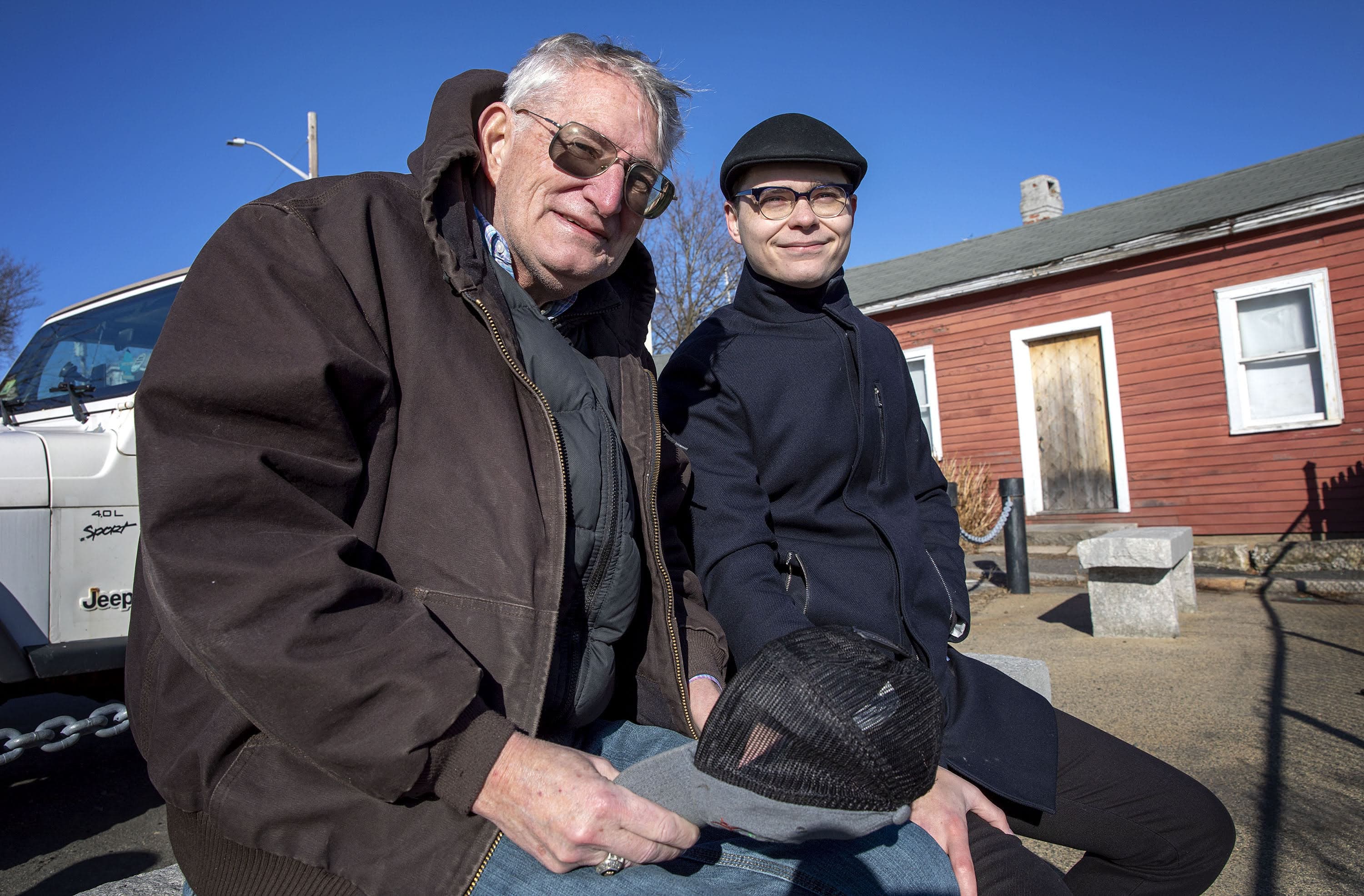 Frank Shaw and Jeremiah MacKinnon enjoy the sunshine on a stone bench overlooking Salem Harbor. (Robin Lubbock/WBUR)