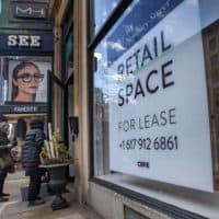Two shoppers walk into a store next to a vacant retail spot for lease on Newbury Street. (Jesse Costa/WBUR)