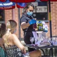 A server brings beverages to a group of people dining for lunch at Mother Anna’s in the North End on the first day of phase two of reopening in June, which allowed restaurants to serve patrons on the premises outdoors. (Jesse Costa/WBUR)