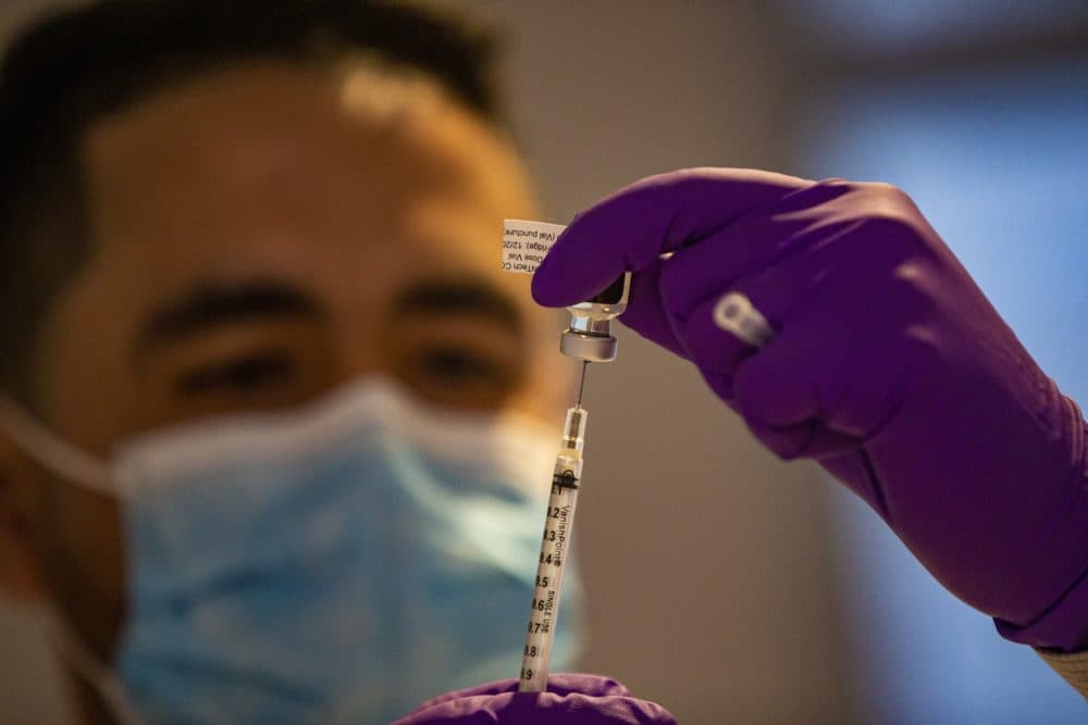 Nicholas Capote dispenses the first Pfizer COVID-19 vaccine doses at Tufts Medical Center from a vial into a syringe. (Jesse Costa/WBUR)
