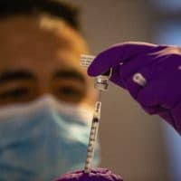 Nicholas Capote dispenses the first Pfizer COVID-19 vaccine doses at Tufts Medical Center from a vial into a syringe. (Jesse Costa/WBUR)