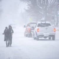 With the sidewalk deep in snow, pedestrians walk along the side of the road on Concord Ave. (Robin Lubbock/WBUR)