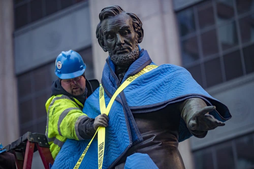 Workers tie down the 2,800-pound statue onto a flat bed truck. (Jesse Costa/WBUR)