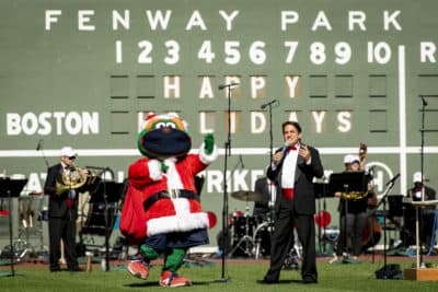 Red Sox mascot Wally the Green Monster makes a cameo appearance for “Must Be Santa” while Lockhart and the orchestra members sing along.
(Courtesy Maddie Malhotra/Boston Red Sox)