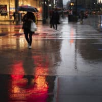 A shopper walks in a rainstorm, Nov. 30, 2020 in New York. (Mark Lennihan/AP)