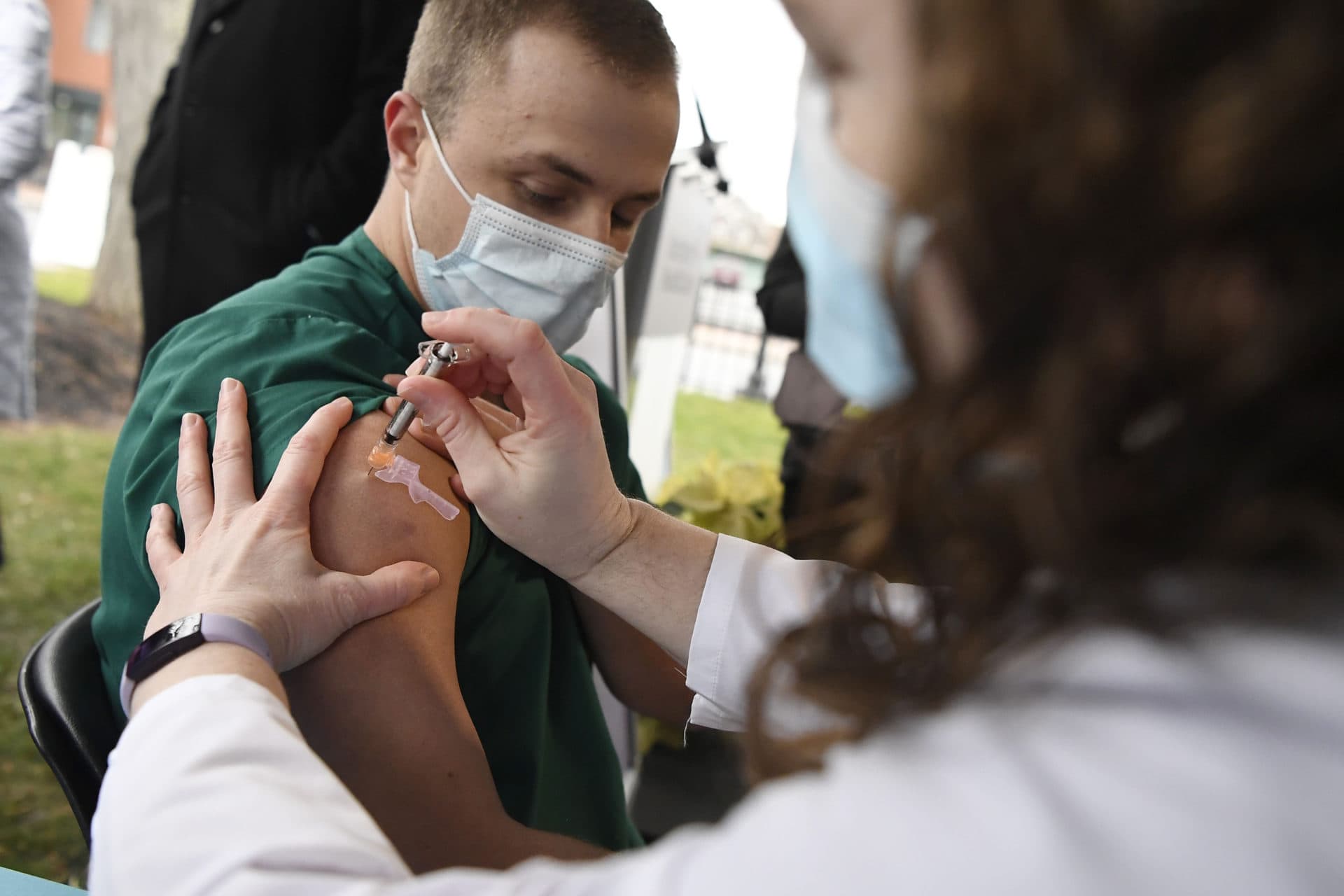 Colleen Teevan, system pharmacy clinical manager at Hartford HealthCare, administers the Pfizer-BioNTech vaccine for COVID-19 to health care worker Connor Paleski outside of Hartford Hospital in Connecticut. (Jessica Hill/AP)