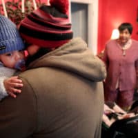 David Nelligan picks up his son, while Dorothy Williams looks on at Dottie's Family Childcare in Dorchester in March 2020. Dorothy normally cares for 10 children but was down to two that day as parents increasingly worked from home and removed their children from situations in which they could contract coronavirus. (Craig F. Walker/The Boston Globe via Getty Images)