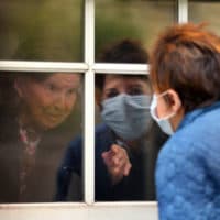 Ellen Taylor talks to her mother, Eva Taylor, age 100, through the first floor window in Jamaica Plain in Boston on May 8, 2020. The Rogerson House accommodated families that wanted to visit their mothers and grandmothers for Mothers Day. Because of coronavirus, family members have not been allowed inside. (John Tlumacki/The Boston Globe via Getty Images)