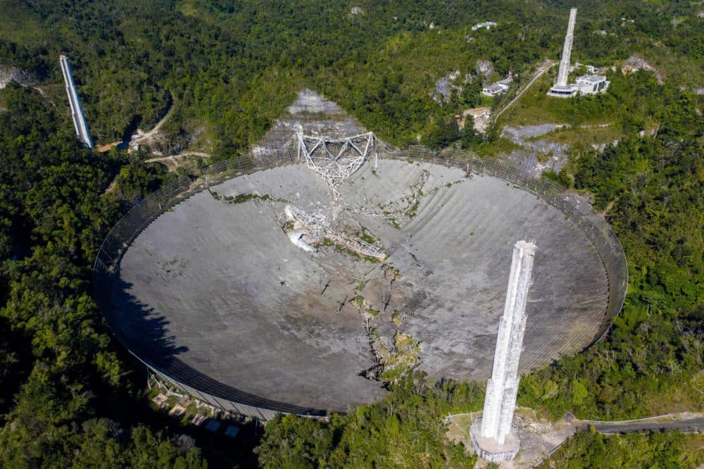 This aerial view shows the damage at the Arecibo Observatory after one of the main cables holding the receiver broke in Arecibo, Puerto Rico, on Dec. 1, 2020. The radio telescope in Puerto Rico, which once starred in a James Bond film, collapsed Tuesday when its 900-ton receiver platform fell 450 feet (140 meters) and smashed onto the radio dish below. (Ricardo Arduengo/AFP via Getty Images)