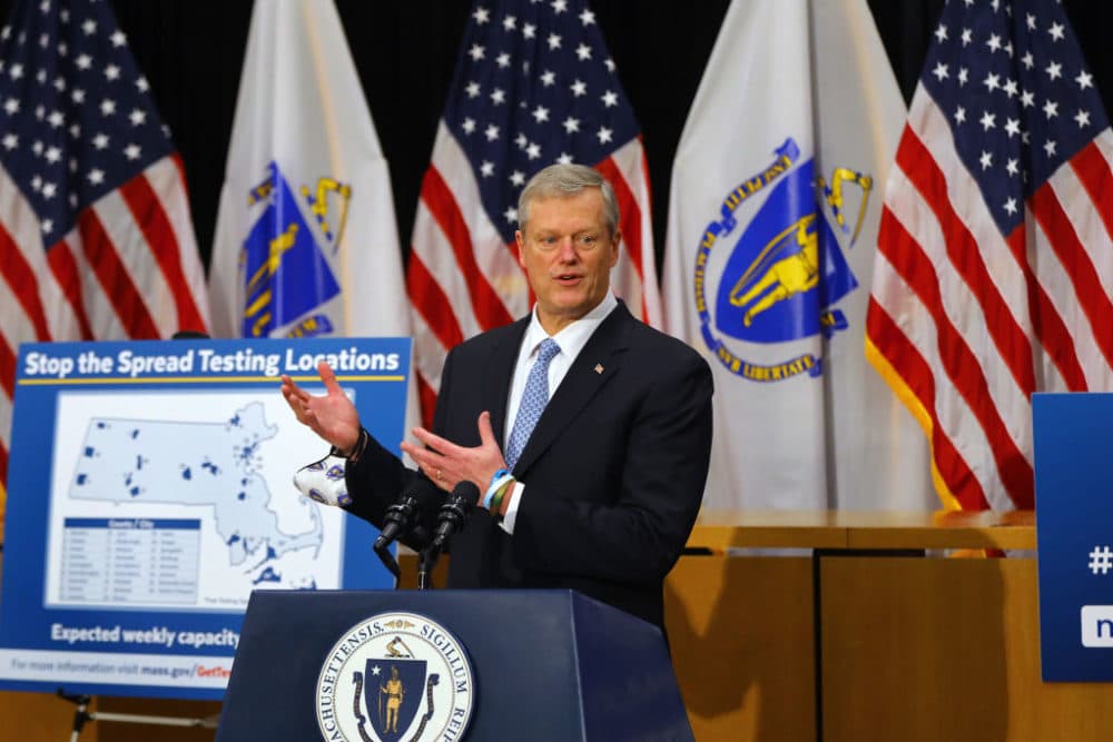 Gov. Charlie Baker stands next to a sign reading "Stop the Spread Testing Locations" as he speaks during a press conference in the Gardner Auditorium in the State House on Dec. 7. (Pat Greenhouse/The Boston Globe via Getty Images)