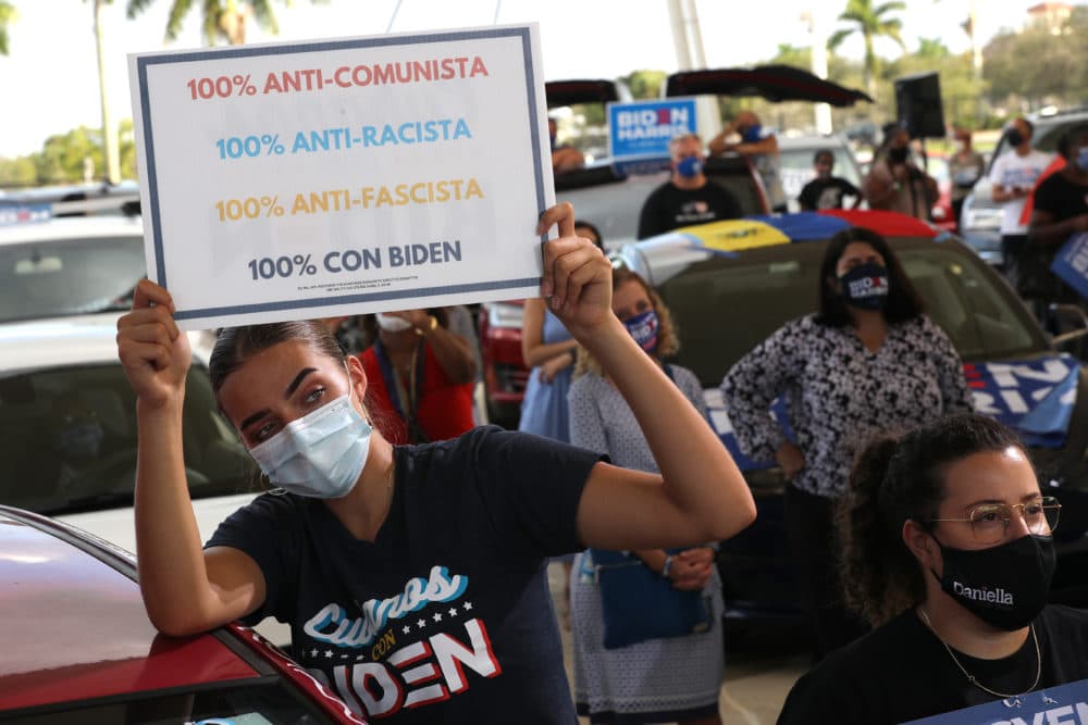 Wearing a face masks to reduce the risk posed by the coronavirus, Sophia Hildalgo (L) and Amore Rodriguez of Miami stay with their car decorated in Cubans for Biden paint as Democratic presidential nominee Joe Biden delivers remarks during a drive-in voter mobilization event at Miramar Regional Park October 13, 2020 in Miramar, Florida. (Chip Somodevilla/Getty Images)