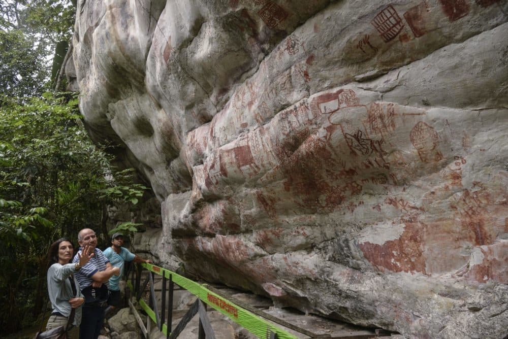 Celine Valadeau (L), an anthropologist from the French Institute of Andean Studies (IFEA), and Ernesto Montenegro (2-L), director of the Colombian Institute of Anthropology and History, look at rock art on the Raudal de Guayabero hill in the Serrania La Lindosa in the Amazonian department of Guaviare, Colombia, on June 8, 2018. (Guillermo Legaria/AFP via Getty Images)
