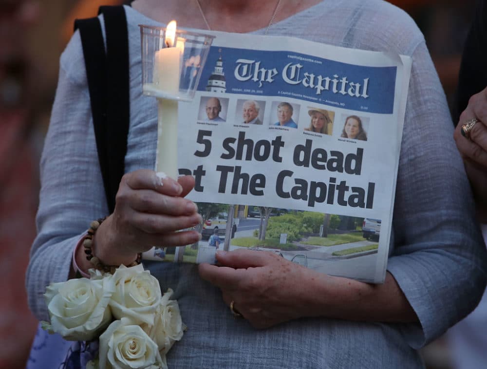 A women holds an edition of the Capital Gazette newspaper during a candlelight vigil to honor the five people who were shot and killed on June 29, 2018 in Annapolis, Maryland. (Mark Wilson/Getty Images)