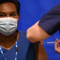 A nurse administers the Pfizer-BioNTech COVID-19 vaccine to a man at a health center on the first day of the largest immunization program in the United Kingdom's history on Dec. 8, 2020 in Cardiff, Wales. (Justin Tallis, Pool / Getty Images)
