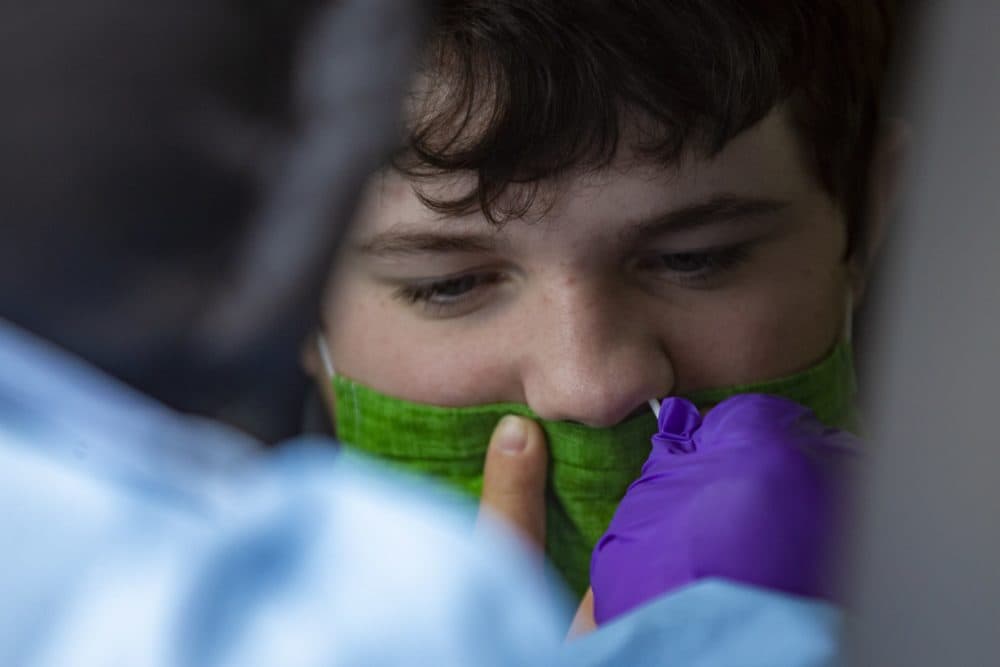 Jessica Capobianco performs a COVID-19 test on 14-year-old Brady Martel at the Bromfield School in Harvard, Mass. (Jesse Costa/WBUR)