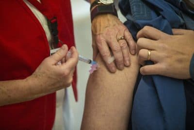 A first responder from Needham Fire Department receives the Moderna COVID-19 vaccine at Rosemary Recreational Center in Needham. (Jesse Costa/WBUR)