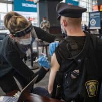 Registered nurse Samantha Schuko prepares to vaccinate Foxborough Police Officer Brendan Fayles with the Moderna COVID-19 vaccine at the Gillette Stadium COVID-19 Vaccination Site. (Jesse Costa/WBUR)