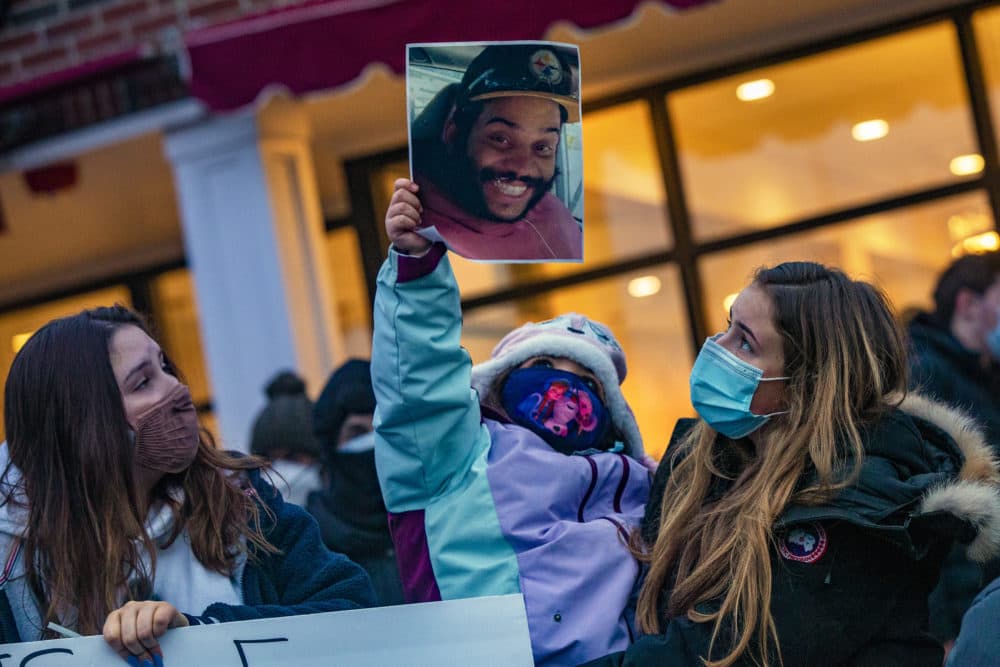 A young girl holds up a photo of Henry Tapia at a vigil in Belmont to honor his memory. (Jesse Costa/WBUR)