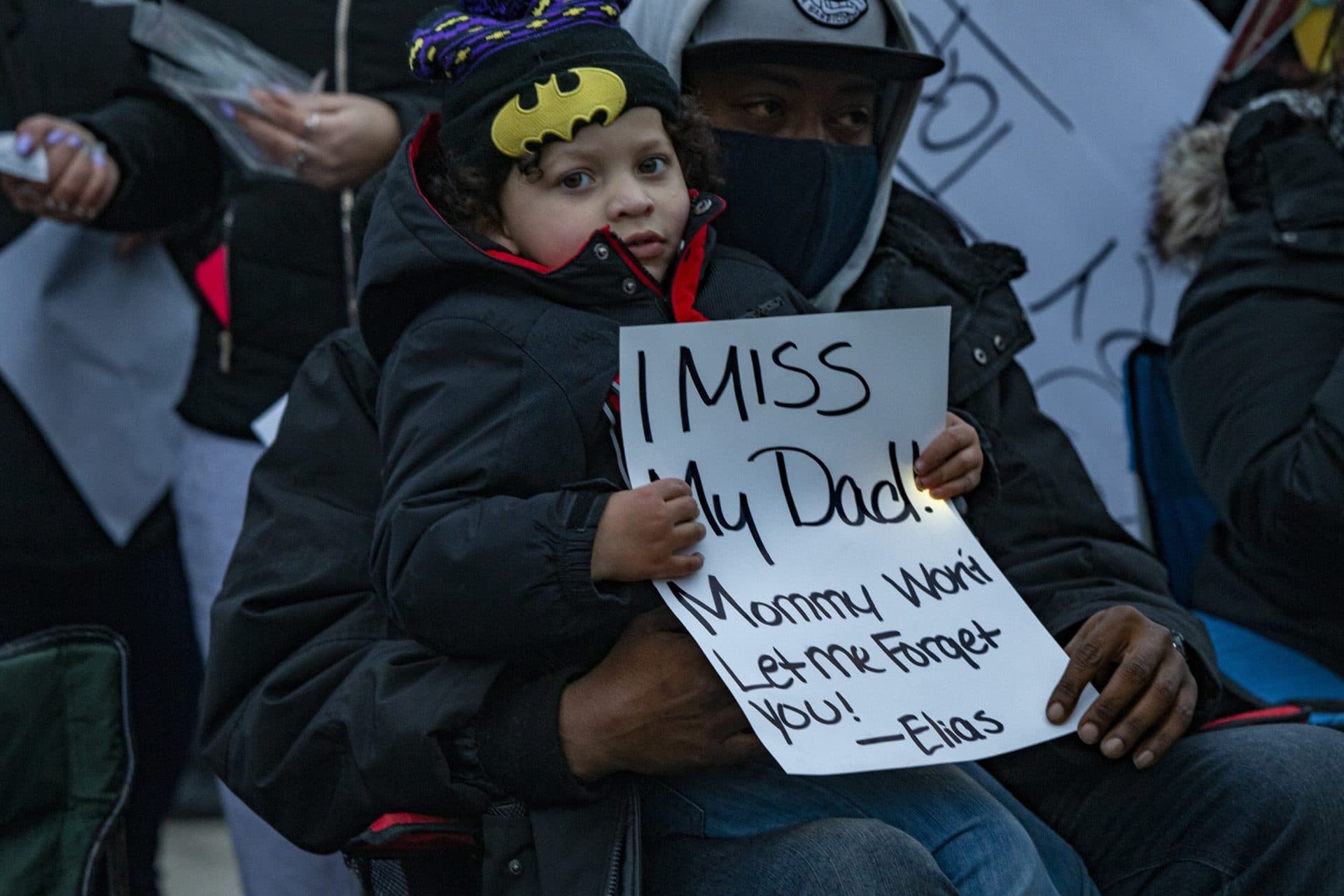 Henry Tapia’s son Elias Morton holds a sign that says “I miss my Dad! Mommy won’t let me forget you!” at a vigil honoring his memory in Cushing Square. (Jesse Costa/WBUR)