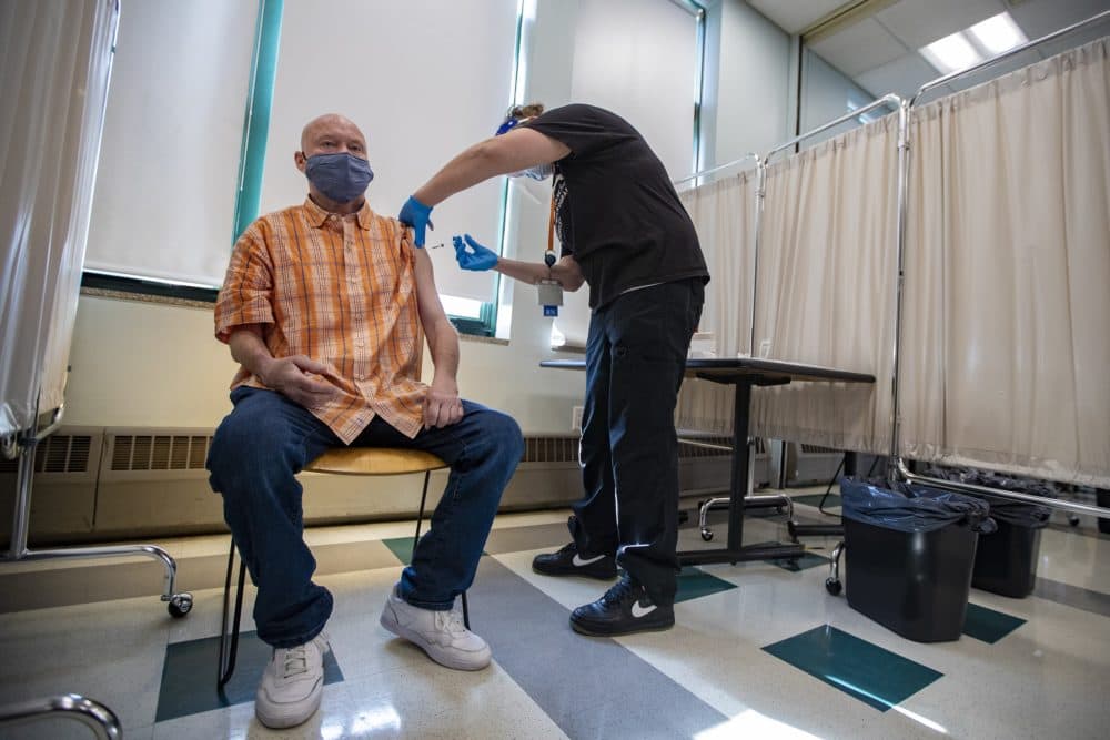 Boston Health Care for the Homeless Program registered nurse Jessica Pasteris administers the COVID-19 vaccine to George Thomas, a Pine Street Inn resident for three-and-a-half years. (Jesse Costa/WBUR)
