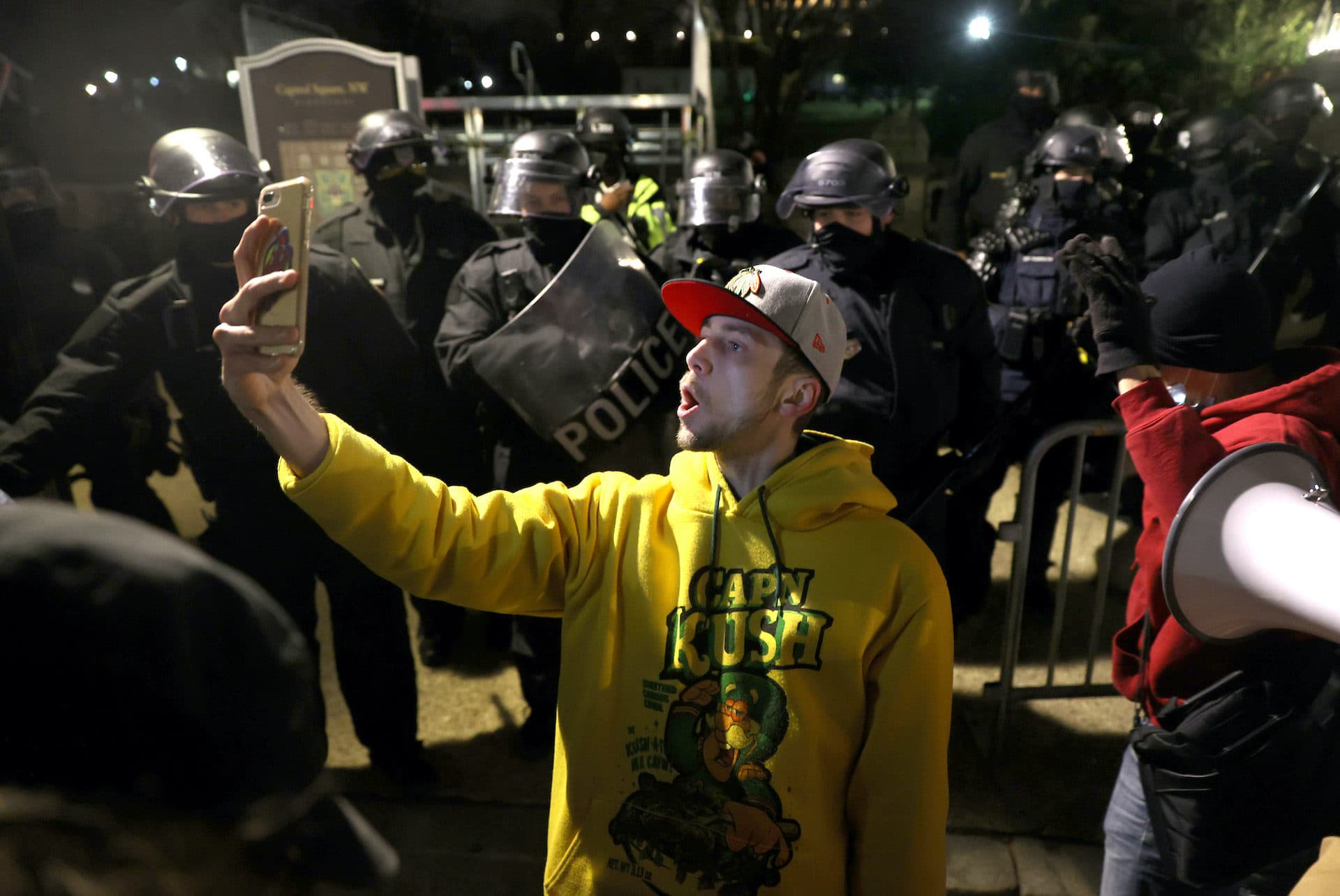 A protester takes a photo with police officers in riot gear dispersing protesters gathering at the U.S. Capitol Building. (Tasos Katopodis/Getty Images)