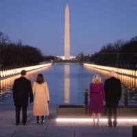 (L-R) Douglas Emhoff, Vice President Kamala Harris, Dr. Jill Biden and President Joe Biden look down the National Mall as lamps are lit to honor the nearly 400,000 American victims of the coronavirus pandemic at the Lincoln Memorial Reflecting Pool January 19, 2021 in Washington, DC. (Chip Somodevilla/Getty Images)