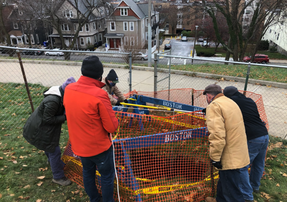 A team of researchers on Dec. 8, lowering a camera rig (an iPhone and some flashlights tied to a paint roller) into the sinkhole. (City of Boston Archaeology Program)