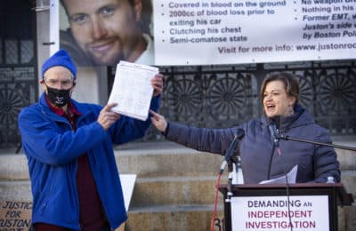 Holding a copy of a petition demanding an independent investigation into Juston Roots's shooting death, Juston Root's father Evan Root and sister Jennifer Root-Bannon addressed a crowd during a rally outside of the Massachusetts State House on Friday. (Robin Lubbock/WBUR)