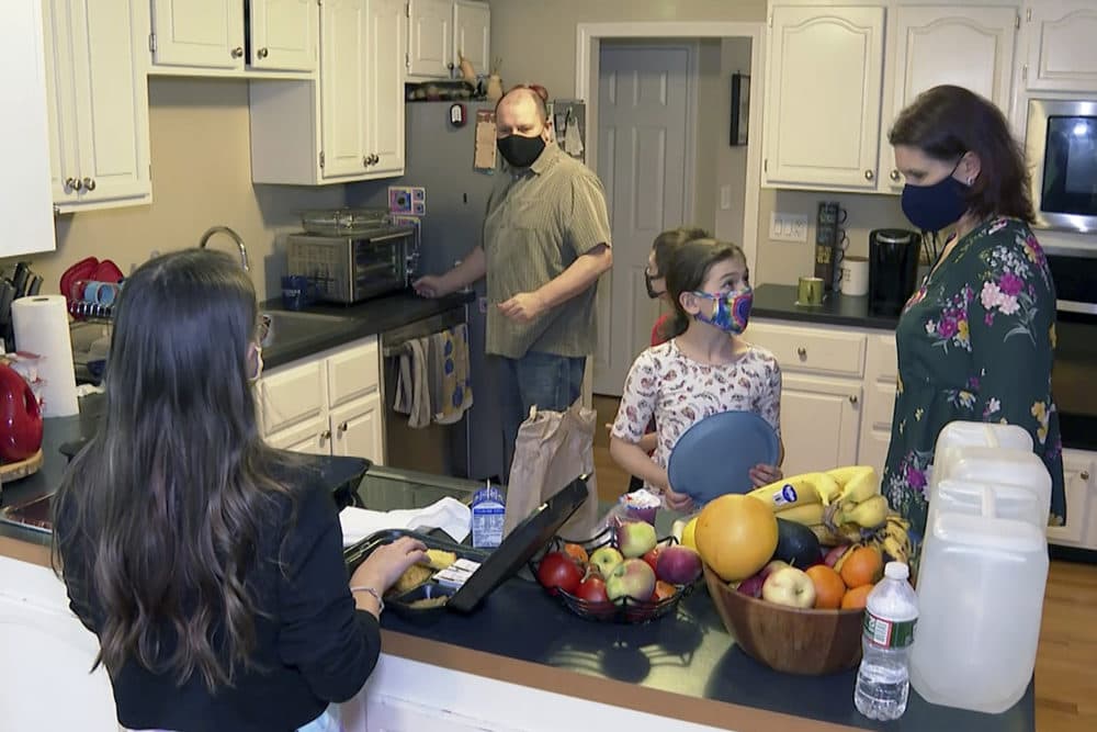 Michael, center, and Jeanine Waterman, right, prepare a family meal at their home in Hanover, Mass., a suburb of Boston, on Oct. 28, 2020. After the St. Francis of Assisi School in Braintree announced its closure in June as the school year ended, Michael and Jeanine’s three children are learning at home. (Rodrique Ngowi/AP)