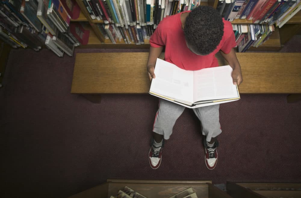 A young boy reading a book in a library. (Getty Images)
