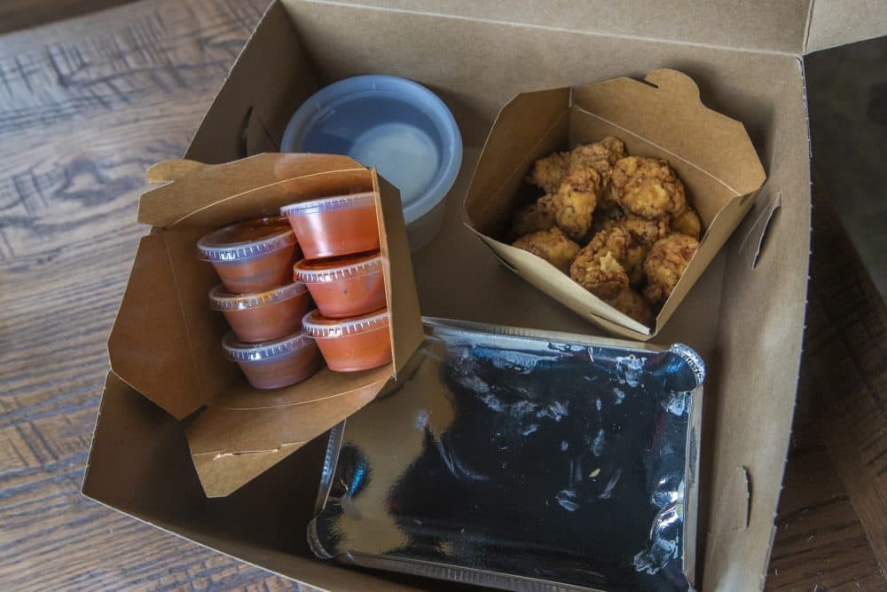 The contents of the "Hell Night" food box. This one contains chicken tenders, rice, six incrementally hot sauces and dill pickle ranch dressing. (Jesse Costa/WBUR)