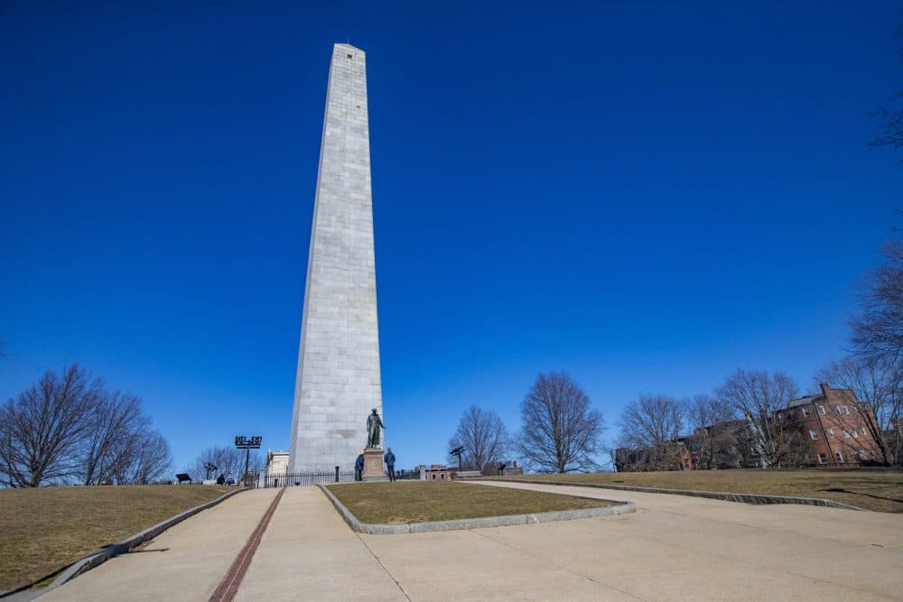 A couple of people stop to read the description on the statue of Dr. Joseph Warren on the mall at the Bunker Hill Monument. (Jesse Costa/WBUR)