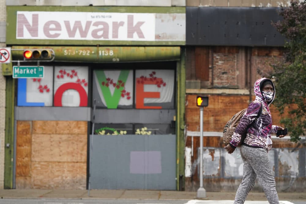 A pedestrian wears a mask as they walk through Newark, N.J., Monday, Oct. 26, 2020. (AP Photo/Seth Wenig)