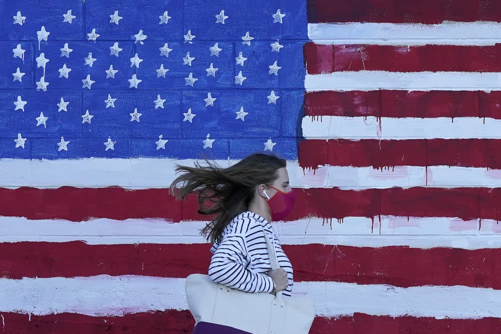 A woman wears a mask while walking past a U.S. flag painted on a wall during the pandemic in San Francisco on Nov. 16, 2020. (Jeff Chiu/AP)