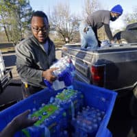 Madonna Manor maintenance supervisor Lamar Jackson left, stacks bottled water brought by Mac Epps of Mississippi Move, as part of the supply efforts by city councilman and State Rep. De'Keither Stamps to a senior residence in west Jackson, Miss. (Rogelio V. Solis/AP Photo)