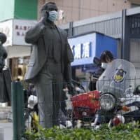 Statues along a street are seen with masks placed on them as a WHO mission visits Wuhan in central China's Hubei province. (Ng Han Guan/AP)