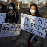 Children carry "stop the hate" and "Asian lives matter" as they walk around Clemente Park in Lowell, Mass. during a vigil held for the victims of the shooting spree in Atlanta at Clemente Park on March 17, 2021. (Erin Clark/The Boston Globe via Getty Images)