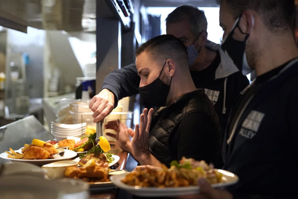 Server Christopher Lee-Caron, of Provincetown, Mass., center left, prepares to carry plates of food to customers at Tin Pan Alley restaurant, April 6, 2021, in Provincetown. (Steven Senne/AP)