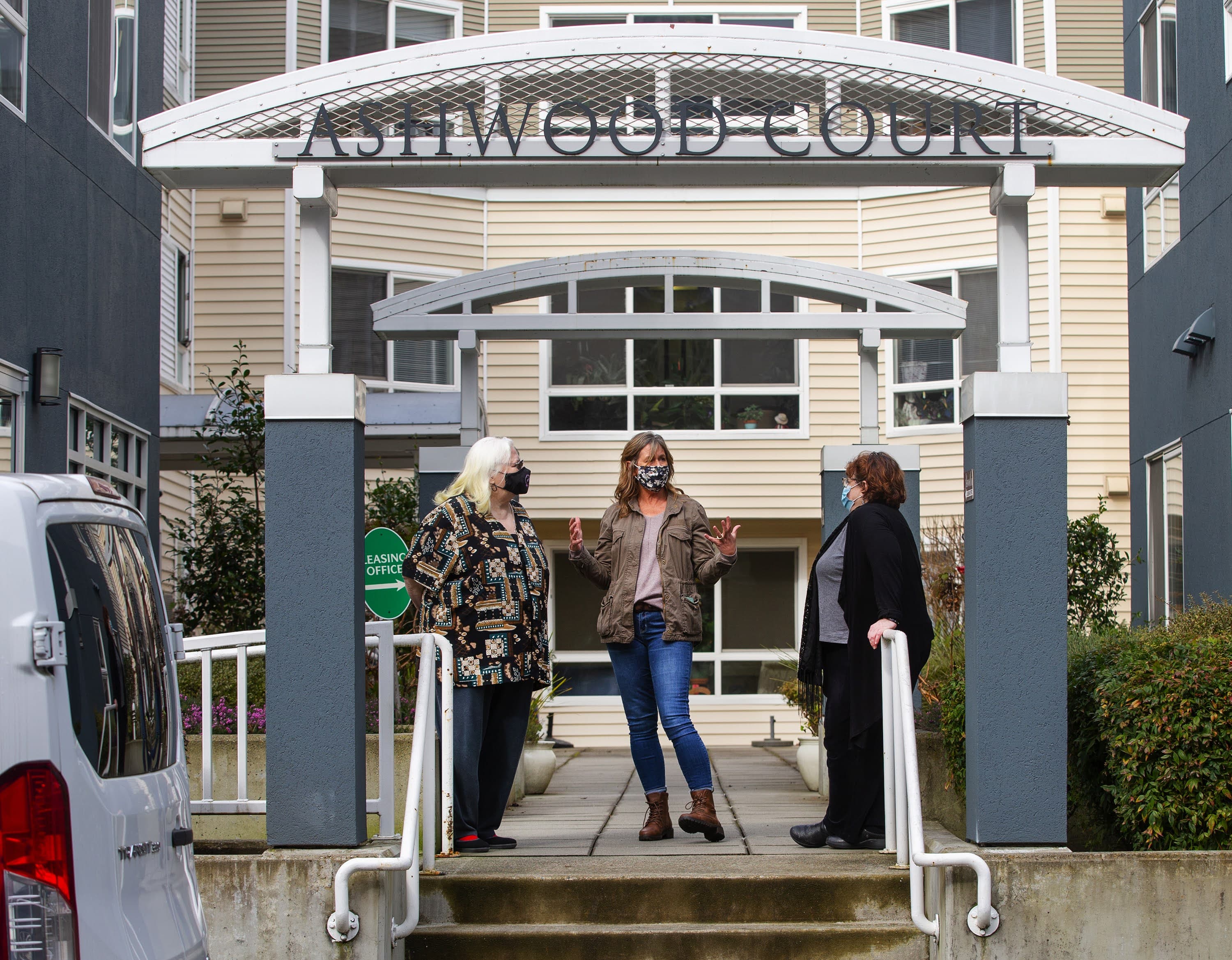 Kim Loveall Price, centro, directora de una organización sin fines de lucro que opera Ashwood Court, un complejo de viviendas para personas de bajos ingresos en Bellevue, Washington, habla con los residentes Susanne Sherman, derecha, y Joyce Hansbearry. (Mike Seigel para WBUR)