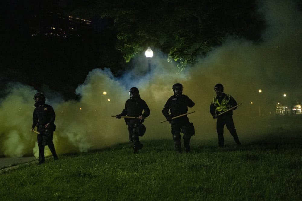 Boston Police emerge from the cloud of tear gas in the Boston Common to clear out protesters the night of May 31, 2020 (Jesse Costa/WBUR)