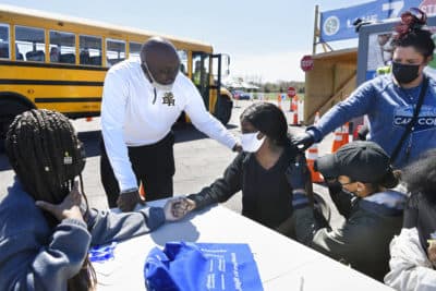 East Hartford High School senior Sudeen Pryce, right, center, receives support from classmate Alexia Phipps, left, East Hartford High School Intervention Coordinator Mark Brown, second from left, and EMT Katrinna Greene, top right, of Manchester, as RN Kaylee Cruz of Bristol administers a shot to Pryce at a mass vaccination site at Pratt & Whitney Runway in East Hartford, Conn., Monday, April 26, 2021. (AP Photo/Jessica Hill)