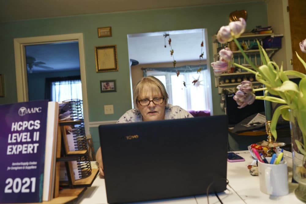 Ellen Booth, 57, studies at her kitchen table to become a certified medical coder, in Coventry, R.I., May 17, 2021. When the restaurant she worked for closed last year, Booth said it gave her "the kick I needed." She started a year-long class to learn to be a medical coder. (David Goldman/AP)