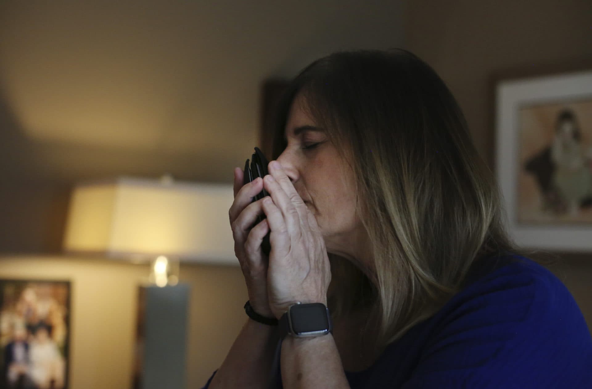 Michelle Pepe tries to smell her late father's wallet while going through his belongings one year after he died of the coronavirus, in Sharon, Mass., on April 14, 2021. After contracting the virus herself, Pepe lost and has not regained her sense of smell. She keeps her father's belongings in hopes that one day it comes back and she can smell him again. (Jessie Wardarski/AP)