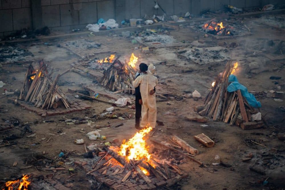 Family members embrace each other amid burning pyres of victims who lost their lives due to the Covid-19 coronavirus at a cremation ground in New Delhi on April 26, 2021. (Photo by Jewel Samad/AFP via Getty Images)