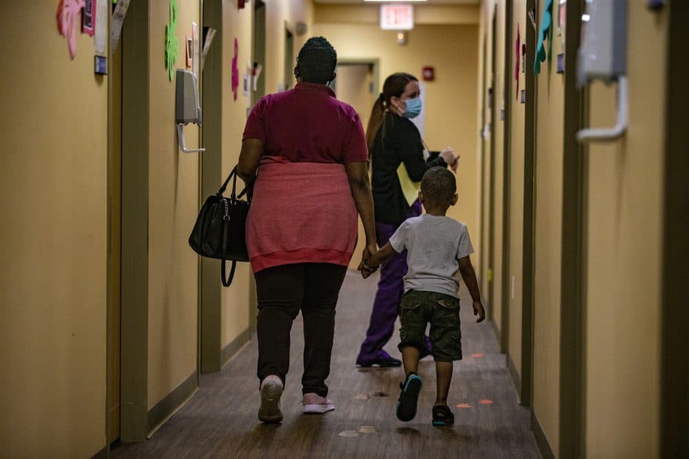 A health worker leads a mother and her child to an examination room at the Brockton Neighborhood Health Center. (Jesse Costa/WBUR)