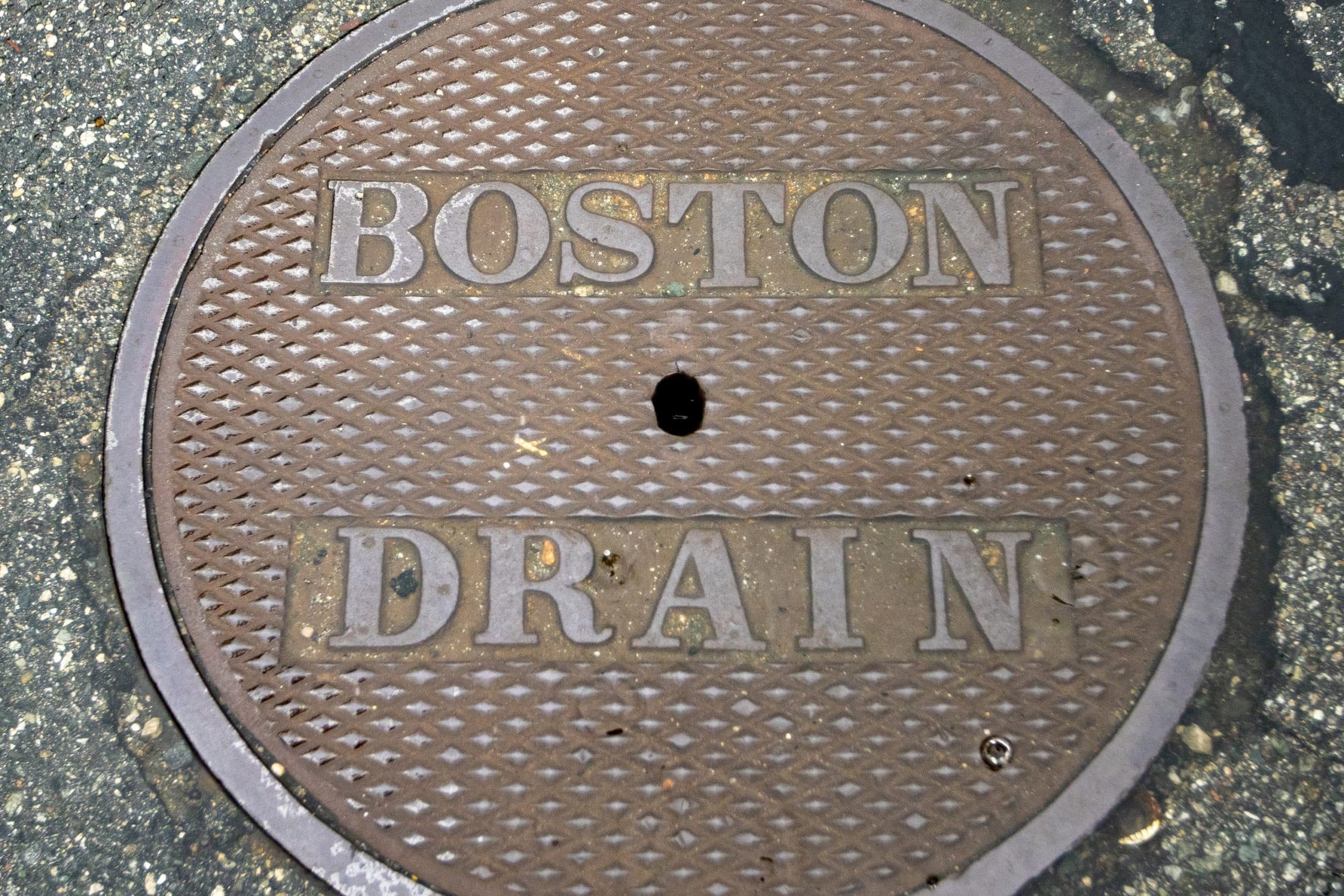 Rainwater collects on a manhole cover on Marginal Street in East Boston. (Jesse Costa/WBUR)