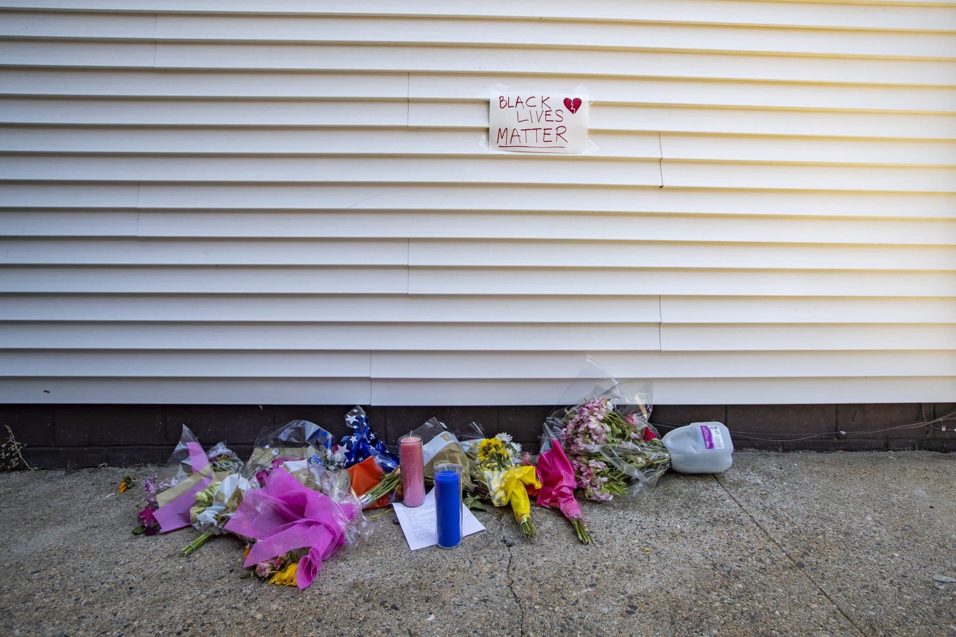 Flowers and candles lay in an alley off of Shirley Street in Winthrop where retired Massachusetts State Police officer David Green was fatally shot. (Jesse Costa/WBUR)